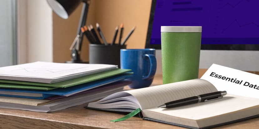 A clean office workspace featuring a laptop, notebooks, pens, and stacked financial documents for business planning.