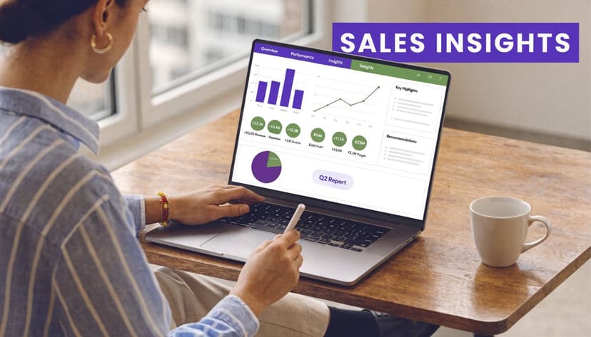 A woman working on a laptop displaying colorful sales data charts and analytical reports on a wooden desk.