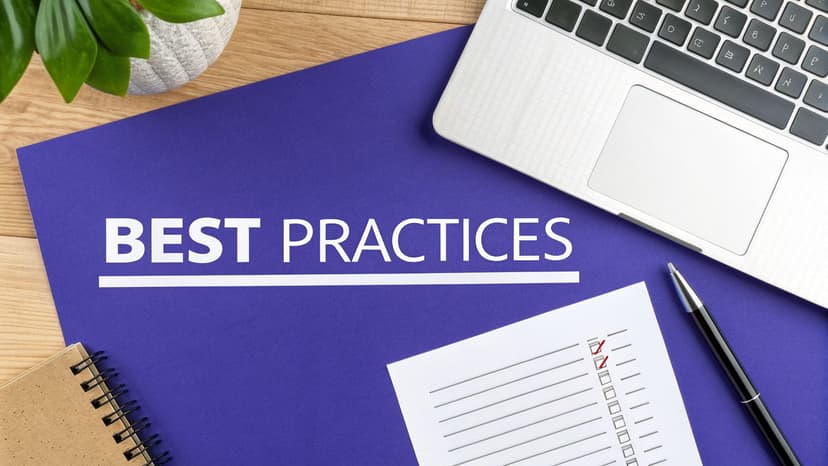 Flat lay of a desk with 'BEST PRACTICES' on a purple folder, a laptop, and a checklist.