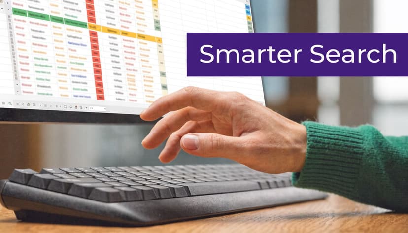 A person typing on a computer keyboard with a spreadsheet interface on the screen displaying Smarter Search.